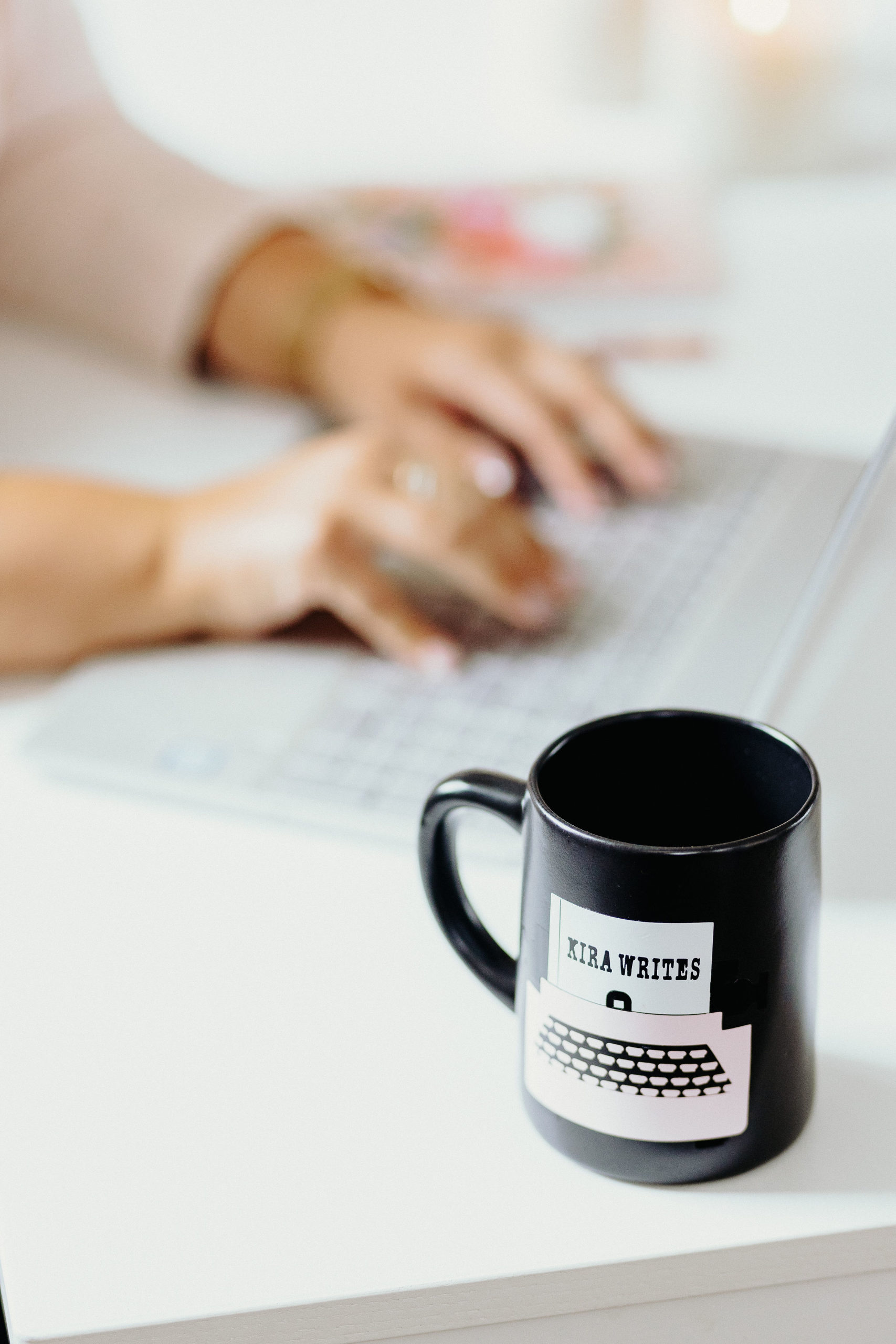 Kira Write mug appearing in focus with Kira typing on a keyboard in the background